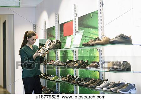 Young female customer selecting sandal in shoe shop View Large Photo Image Stock Photo - Young female customer selecting sandal in shoe shop. Fotosearch