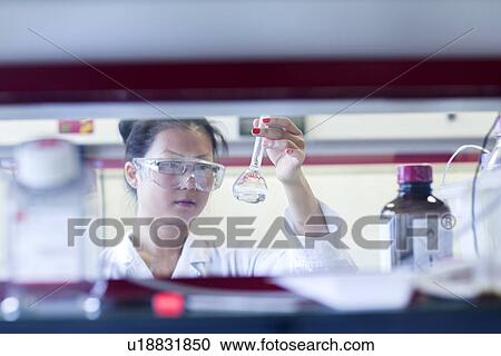 Young female scientist holding up volumetric flask in lab View Large Photo Image Stock Image - Young female scientist holding up volumetric flask in lab. Fotosearch