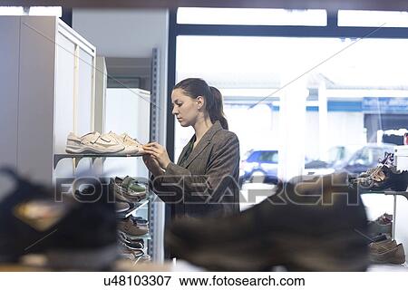 Young female shopper selecting trainer in shoe shop View Large Photo Image Stock Photo - Young female shopper selecting trainer in shoe shop. Fotosearch