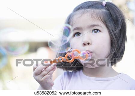 Stock Image - "Young girl blowing bubbles, close-up". Fotosearch