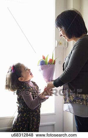 Young girl giving mother flowers View Large Photo Image Stock Photo - Young girl giving mother flowers. Fotosearch