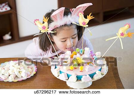 Stock Photo - Young girl licking cake on table. Fotosearch