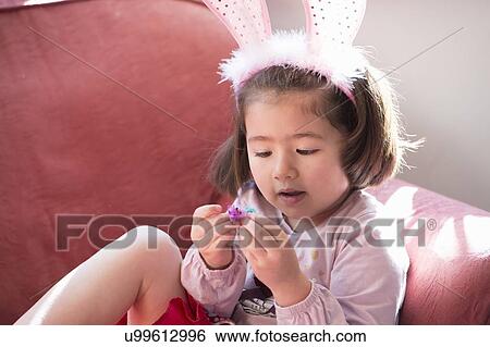 "Young girl wearing bunny ears, looking at fluffy Easter chick" View Large Photo Image Stock Photograph - "Young girl wearing bunny ears, looking at fluffy Easter chick". Fotosearch