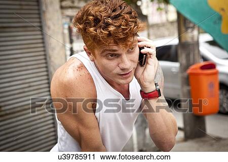 Stock Image - Young man talking on smartphone. Fotosearch