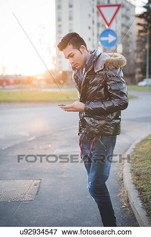 Stock Photo - "Young man using smartphone in the street, Milan, Italy". Fotosearch
