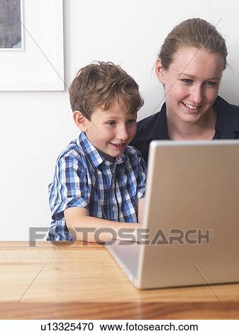 Young woman and son using laptop together at home View Large Photo Image Stock Image - Young woman and son using laptop together at home. Fotosearch