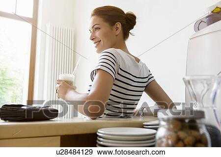 Stock Photo - Young woman drinking coffee in cafe. Fotosearch