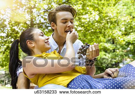 Young woman feeding young man grapes View Large Photo Image Stock Image - Young woman feeding young man grapes. Fotosearch