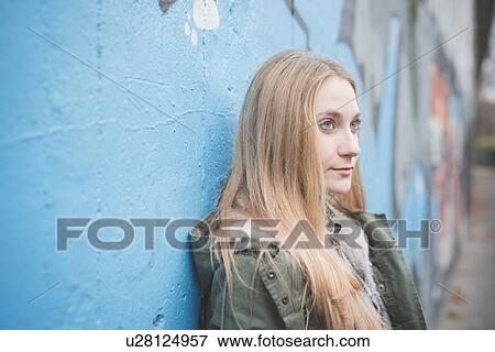 Stock Photo - Young woman leaning against graffiti wall. Fotosearch