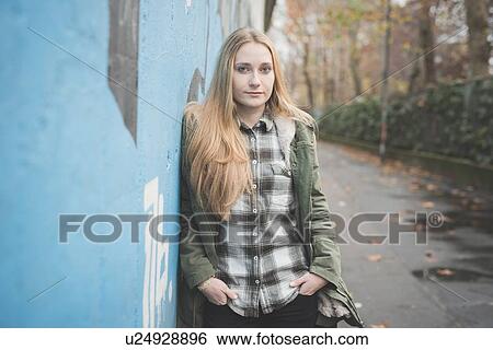 Stock Photograph - Young woman leaning against graffiti wall. Fotosearch