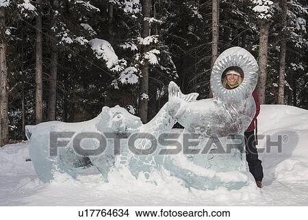 Picture - Young woman looking through ice sculpture. Fotosearch