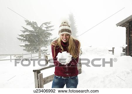 Stock Image - Young woman making a snowball. Fotosearch