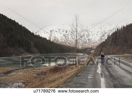 Stock Photograph - "Young woman on road, Girdwood, Anchorage, Alaska". Fotosearch