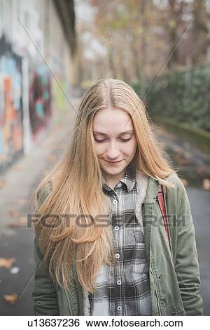 Stock Photograph - "Young woman on street, graffiti wall in background". Fotosearch