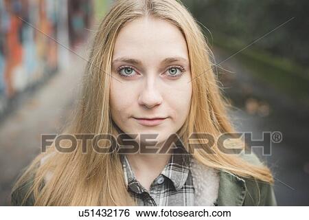 Stock Photograph - "Young woman on street, graffiti wall in background". Fotosearch