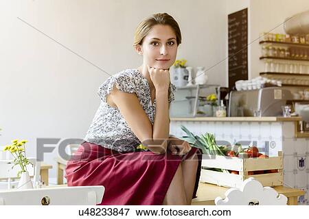 "Young woman sitting on cafe table looking at camera, portrait" View Large Photo Image Stock Photo - "Young woman sitting on cafe table looking at camera, portrait". Fotosearch