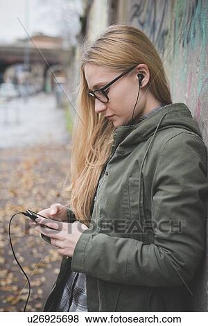 Young woman using smartphone by graffiti wall View Large Photo Image Stock Photo - Young woman using smartphone by graffiti wall. Fotosearch