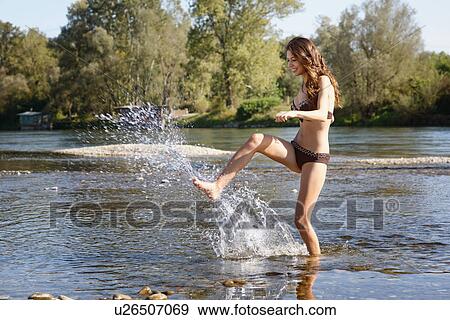 Young woman wearing a bikini splashing and playing in river View Large Photo Image Stock Photo - Young woman wearing a bikini splashing and playing in river. Fotosearch