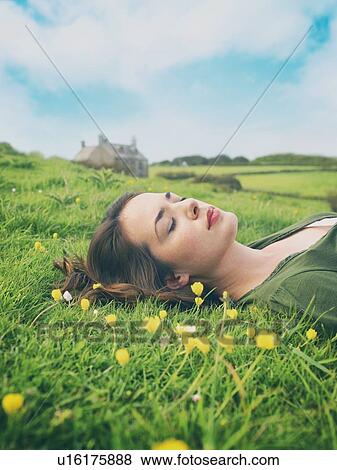 Stock Photo - Young women with eyes closed lying in buttercup grass. Fotosearch