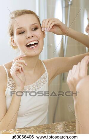 A young woman flossing her teeth View Large Photo Image Stock Photograph - A young woman flossing her teeth. Fotosearch