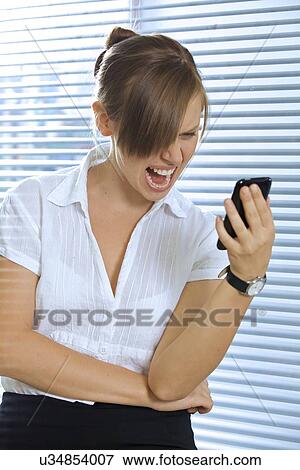 Stock Photo - Angry businesswoman looking at a mobile phone. Fotosearch