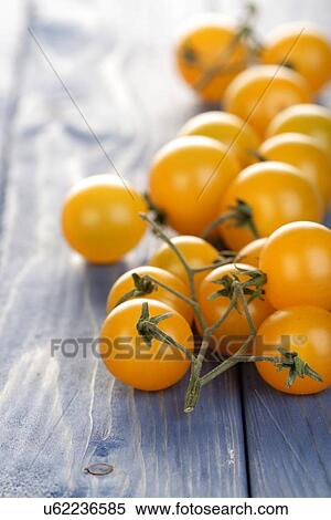Stock Photography - Bunch of yellow cherry tomatoes on wooden table. Fotosearch