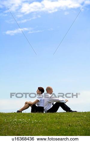 Business couple sitting back to back on grass View Large Photo Image Stock Photograph - Business couple sitting back to back on grass. Fotosearch