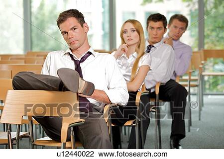 Stock Image - Business executives sitting in row at office. Fotosearch