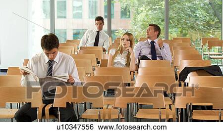 Business executives sitting in conference room, one reading news View Large Photo Image Stock Photograph - Business executives sitting in conference room, one reading news. Fotosearch