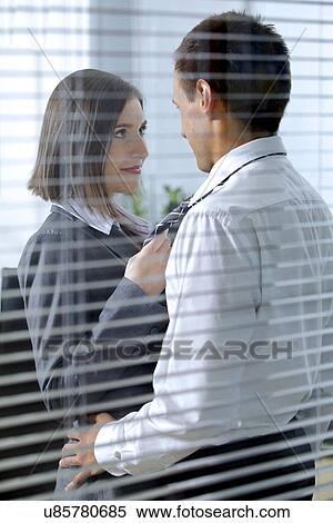 Stock Photography - Businessman and woman standing in office, looking at each other. Fotosearch