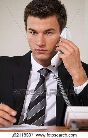 Stock Photo - Businessman conversing on landline phone, portrait. Fotosearch