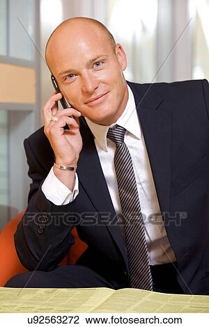 Stock Image - Businessman conversing on mobile phone, portra. Fotosearch