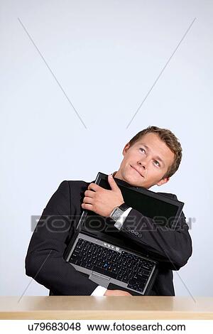 Businessman embracing laptop, looking up View Large Photo Image Stock Photo - Businessman embracing laptop, looking up. Fotosearch