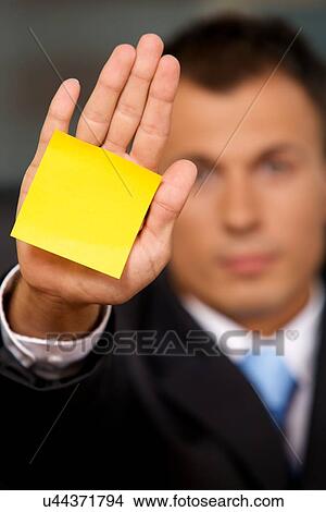Picture - Businessman in office with blank adhesive note stuck to his hand. Fotosearch