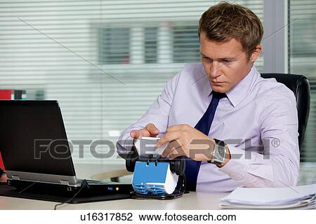 Businessman searching for card by laptop in office View Large Photo Image Stock Image - Businessman searching for card by laptop in office. Fotosearch