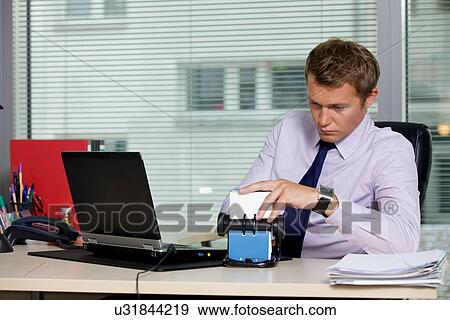 Businessman searching for card by laptop in office View Large Photo Image Stock Photo - Businessman searching for card by laptop in office. Fotosearch