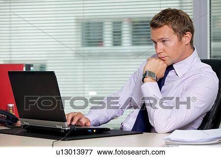 Stock Photo - Businessman sitting with laptop at office. Fotosearch