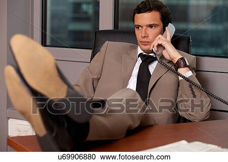 Businessman talking on telephone in an office View Large Photo Image Stock Image - Businessman talking on telephone in an office. Fotosearch