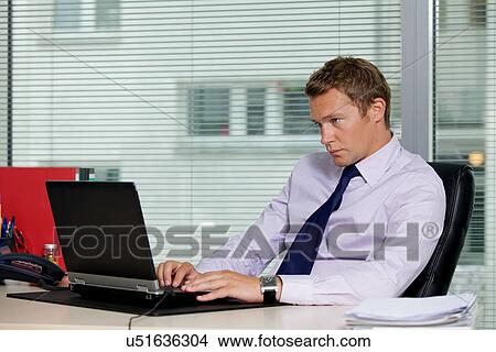 Picture - Businessman using laptop at office. Fotosearch