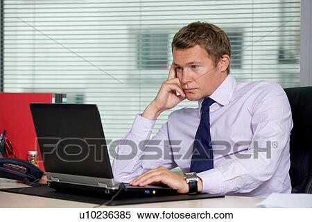 Stock Photography - Businessman using laptop at office. Fotosearch