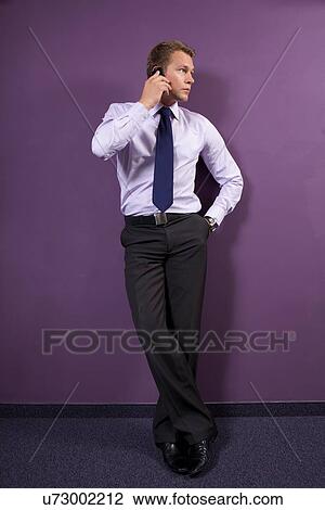 Stock Image - Businessman using mobile phone at office. Fotosearch