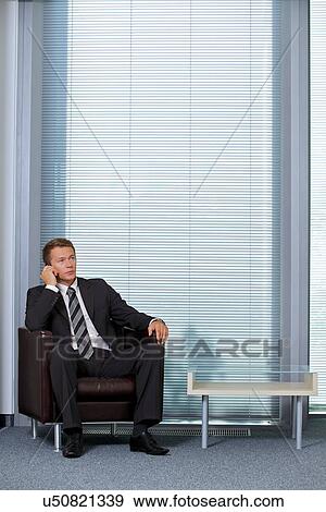 Stock Photo - Businessman using mobile phone in office. Fotosearch