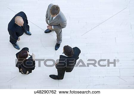Stock Image - Businessmen and businesswoman standing together and conversing. Fotosearch