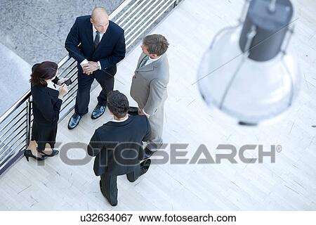 Stock Photo - Businessmen and businesswoman standing together by railing. Fotosearch