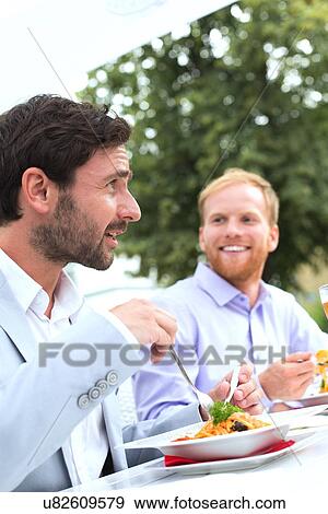 Businessmen having food at outdoor restaurant View Large Photo Image Stock Photo - Businessmen having food at outdoor restaurant. Fotosearch