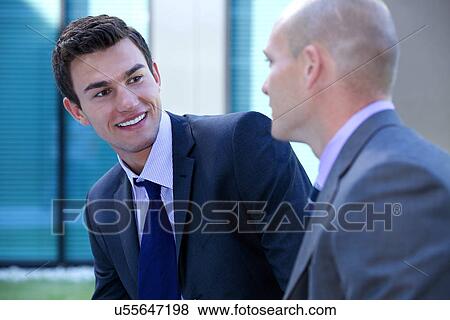 Stock Photo - Businessmen in conversation looking at each other. Fotosearch