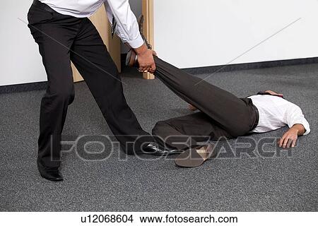 Businessmen pulling colleague's leg at office View Large Photo Image Picture - Businessmen pulling colleague's leg at office. Fotosearch