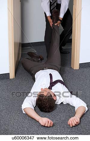 Stock Photo - Businessmen pulling colleague's leg at office. Fotosearch