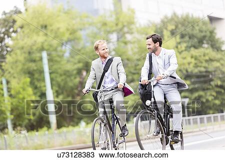 Businessmen talking while cycling outdoors View Large Photo Image Stock Image - Businessmen talking while cycling outdoors. Fotosearch