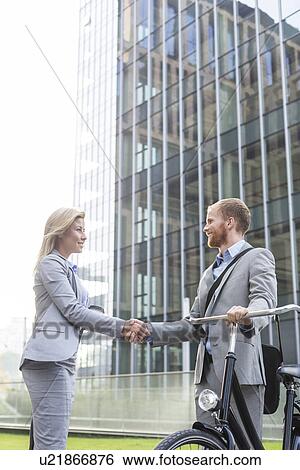 Businesspeople shaking hands outside office building View Large Photo Image Stock Photograph - Businesspeople shaking hands outside office building. Fotosearch